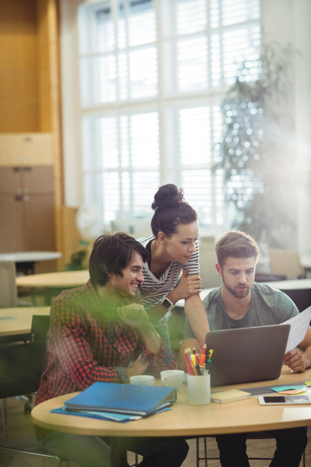 Group of business executives discussing over laptop at their desk